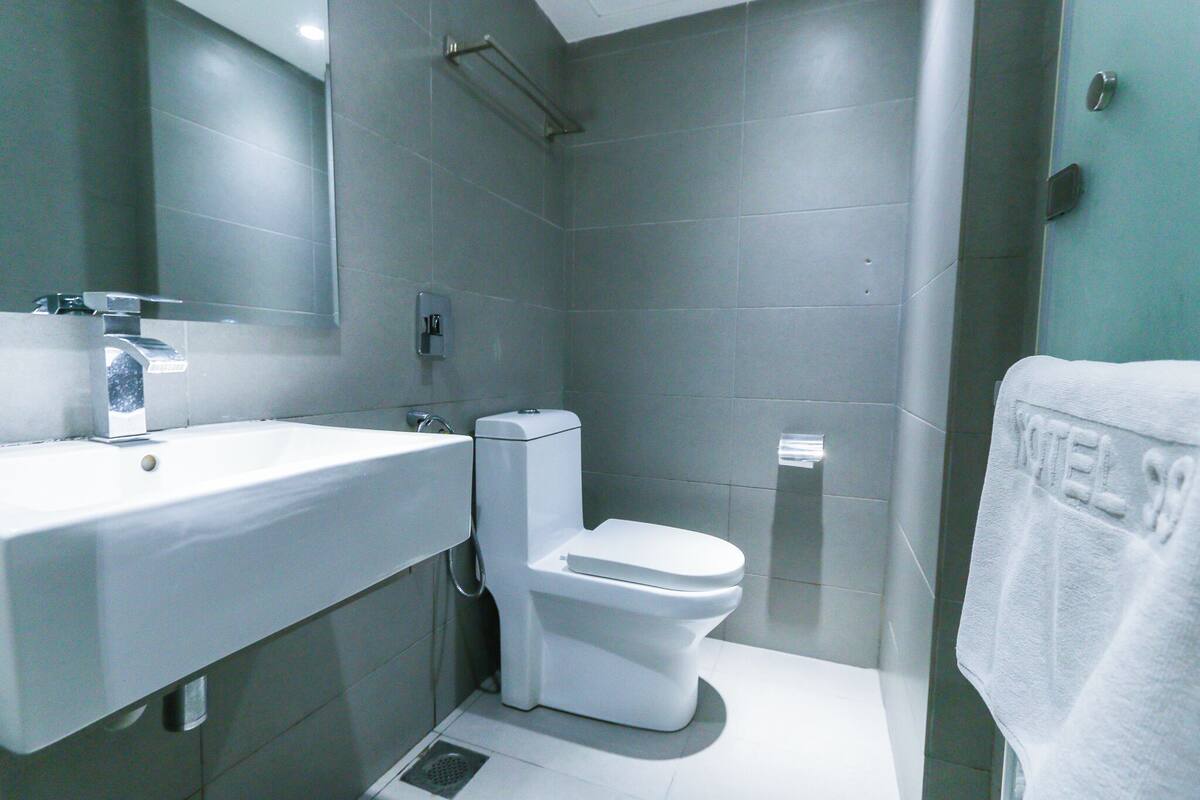 Un bagno moderno con lavandino, water e zona doccia, tutto in bianco.