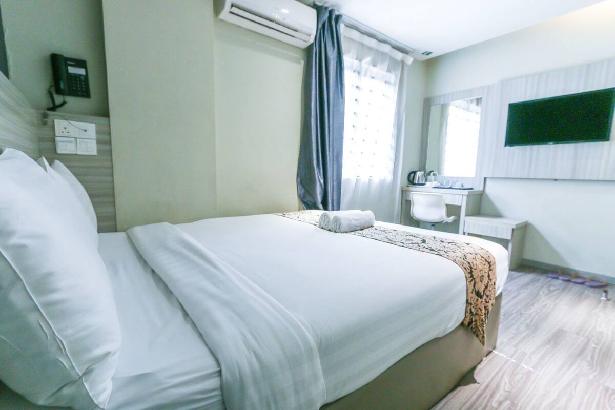 Camera d'albergo con un letto, una scrivania, una sedia, uno specchio e un condizionatore d'aria.
