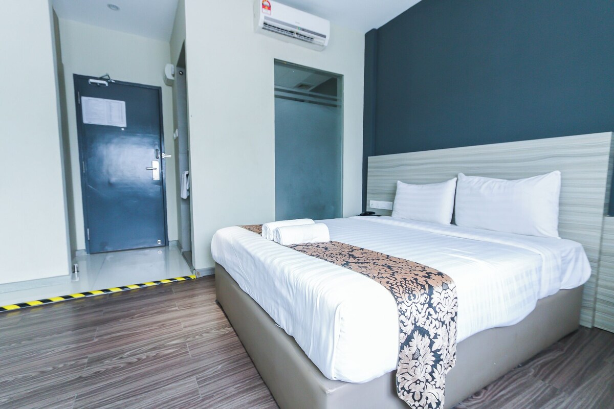 A hotel room with a bed, a wardrobe, and an air conditioning unit.