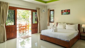 A hotel room with a wooden bed, a green accent wall, a painting, and a view of the outdoors. - Breeze Bay Villa (Ko Pha-ngan)