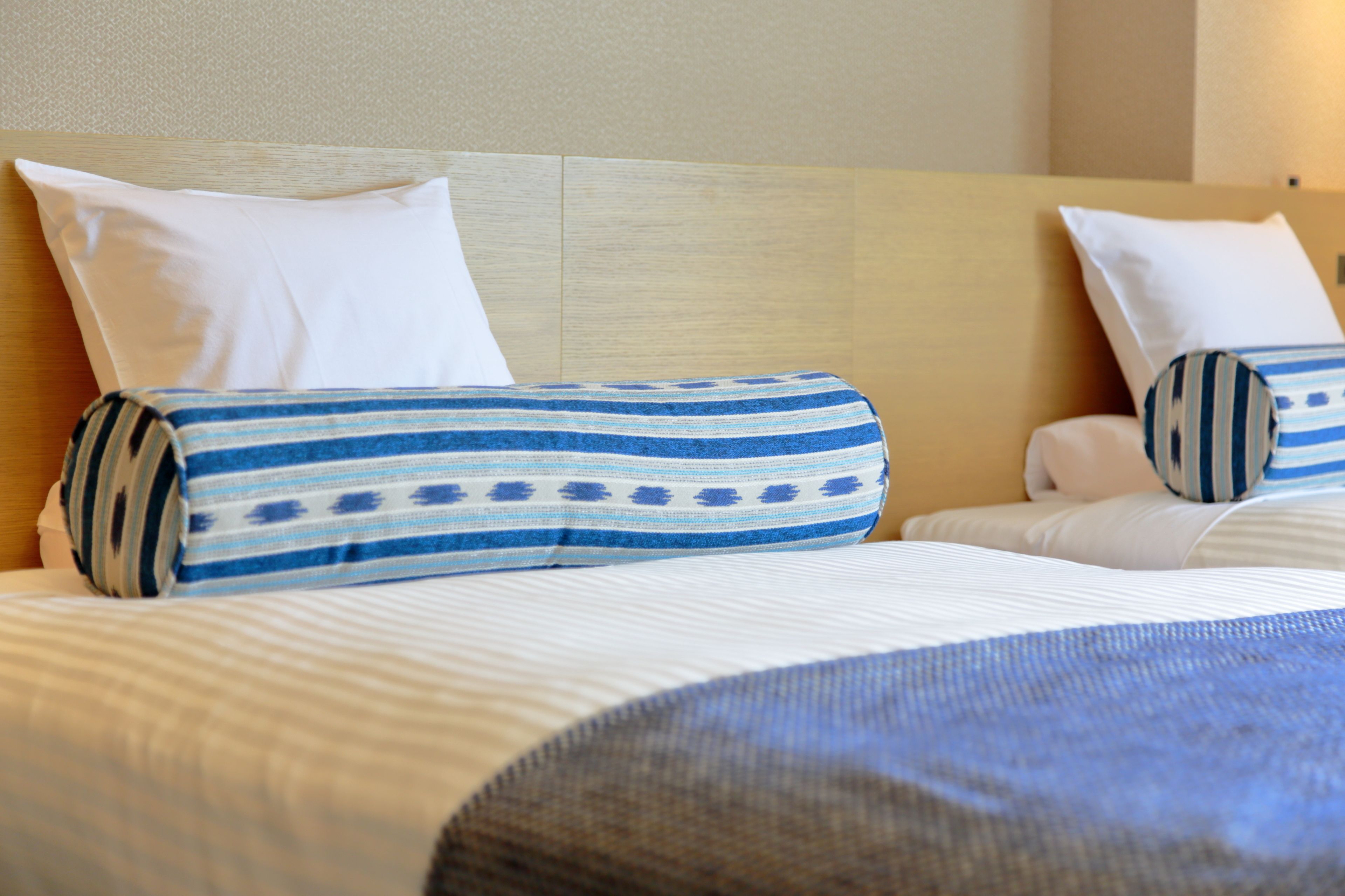 Une chambre d’hôtel avec un lit agrémenté d’oreillers à rayures et d’une tête de lit sobre.