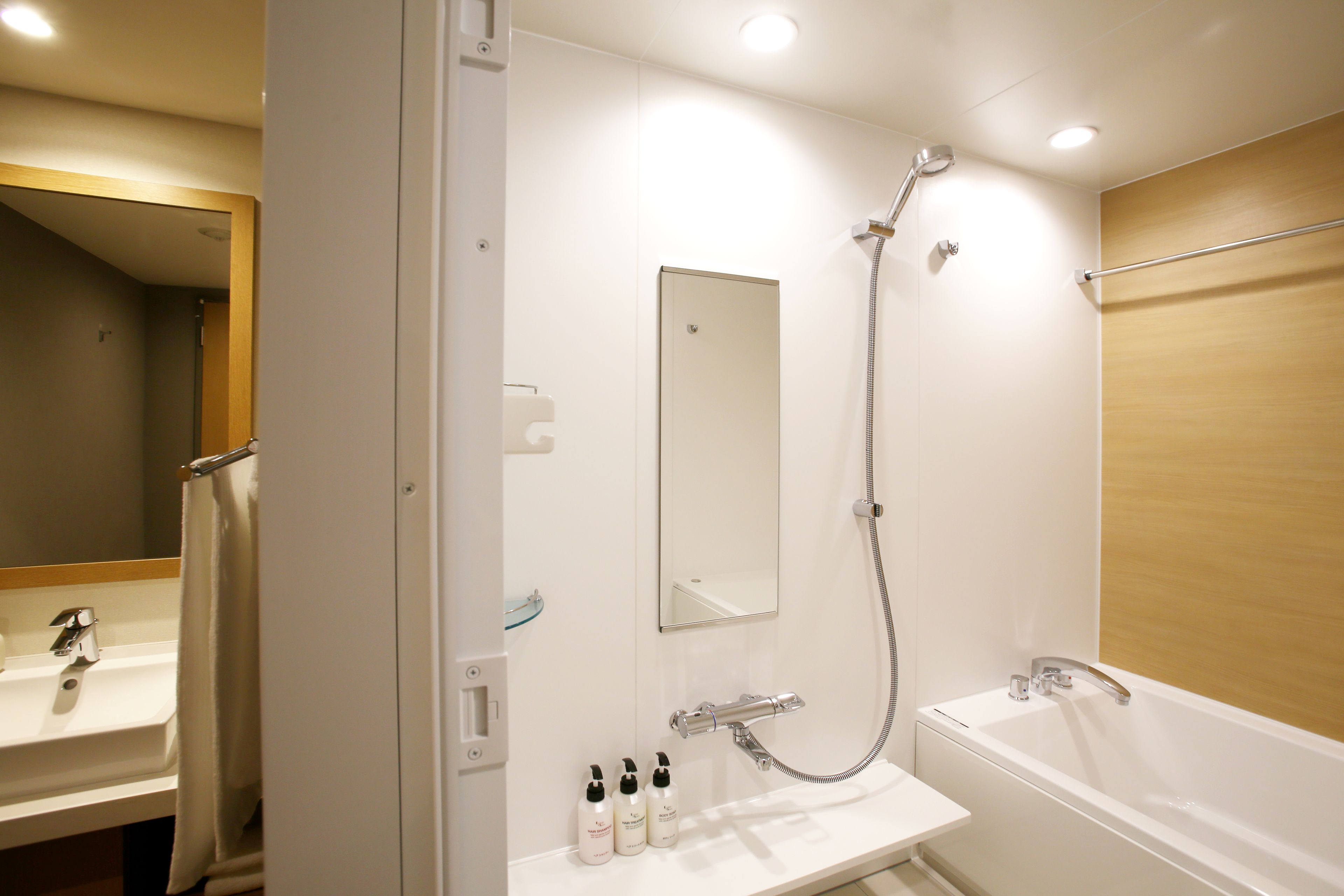 A modern bathroom with a white sink, mirror, and shower.
