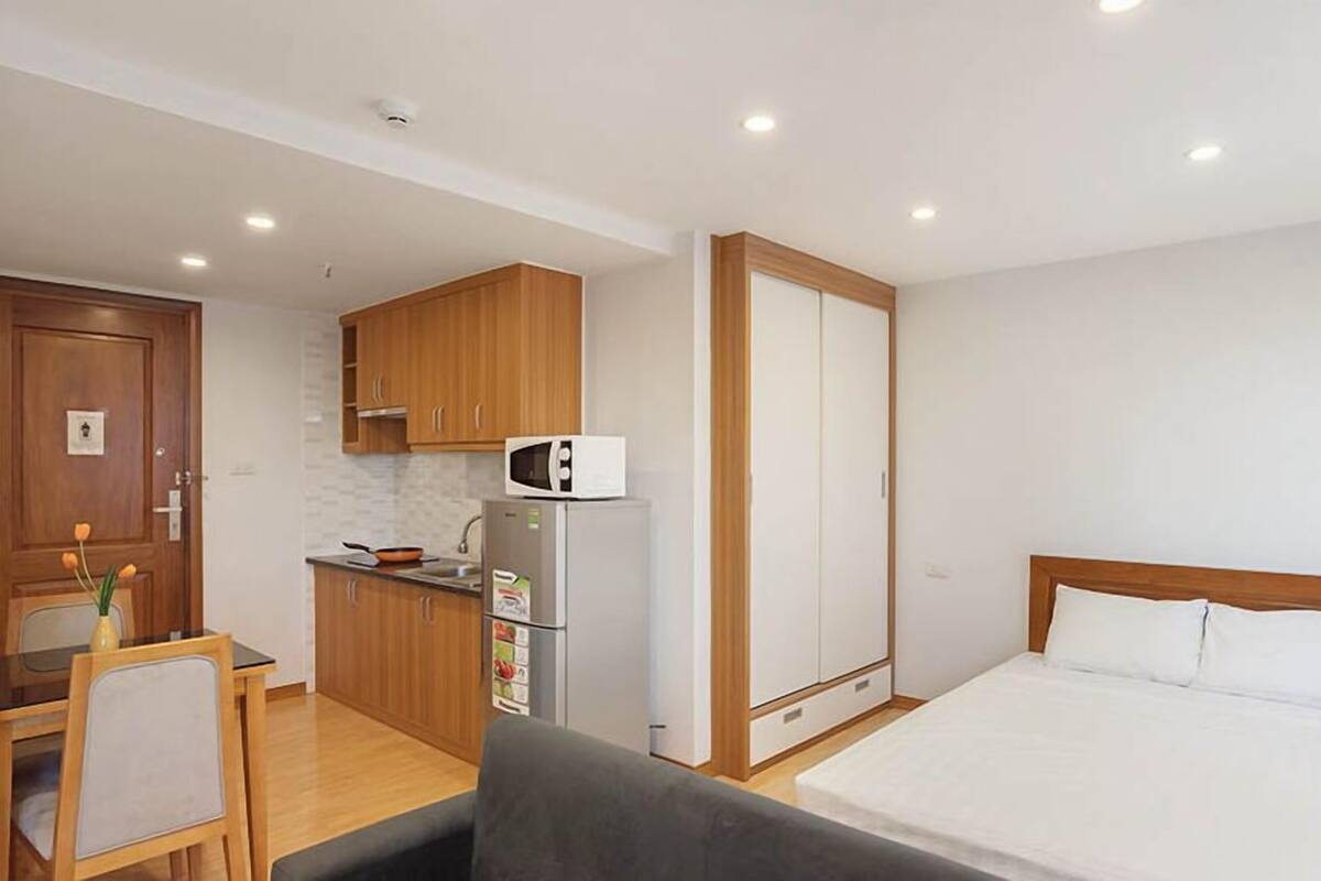 Una habitación compacta con kitchenette, una cama y una pequeña zona de comedor.