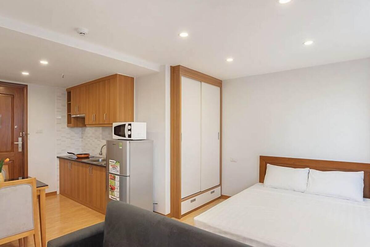 Una habitación de hotel compacta con kitchenette, una cama y un pequeño comedor.