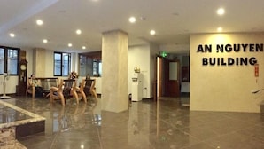 Un vestíbulo amplio con piso pulido, una mesa de recepción y un letrero en la pared que dice "AN NGUYEN BUILDING".