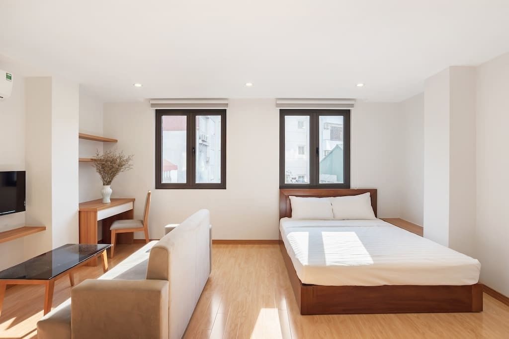 A modern bedroom with a bed, a desk, a chair, and a TV.