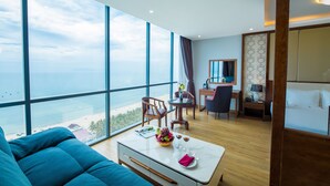 A modern hotel room with a large balcony, a dining area, and a bed. - Le Hoang Beach Hotel (Da Nang)