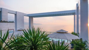 A modern outdoor pool area with a view of the sea, surrounded by concrete structures and green plants. - Le Hoang Beach Hotel (Da Nang)