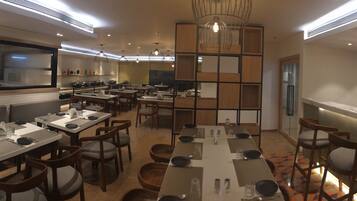A restaurant with multiple dining tables, chairs, and a bar area.