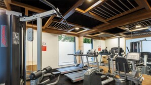 Et fitnesscenter med løbebånd, crosstrainere og styrketræningsudstyr.
