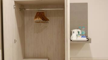 Ein kleines Hotelzimmer mit integriertem Kleiderschrank, einer Minibar und einer Wand-Klimaanlage.