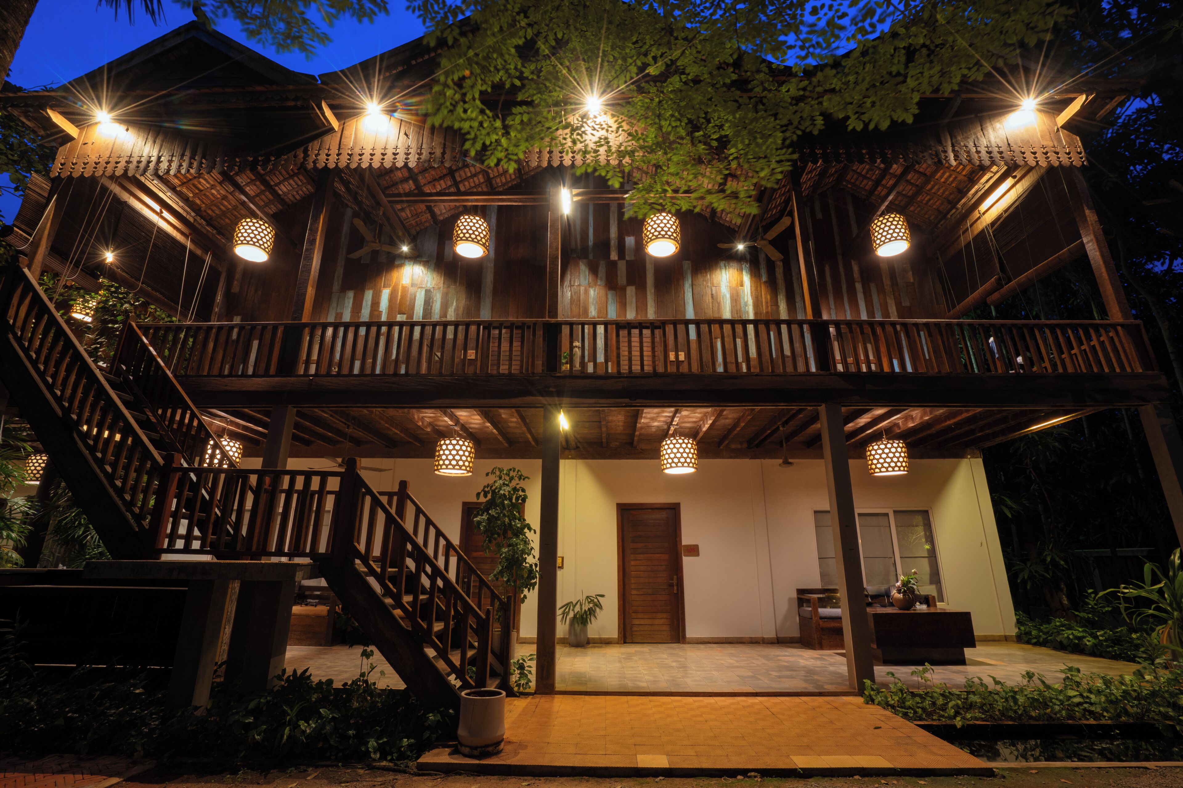 Un edificio de madera de dos pisos con balcón, escalera y varias luces colgantes.