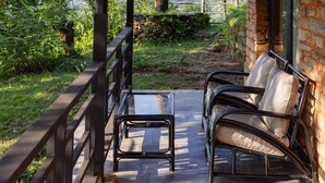 A covered patio with a brick wall, a wooden ceiling, and a view of mountains. - Tiger Mountain Pokhara Lodge (Pokhara)