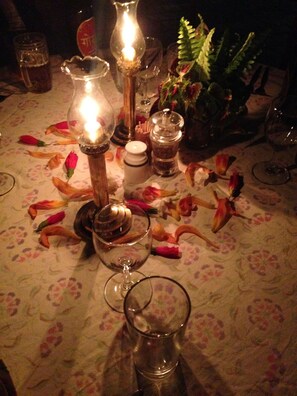 A beautifully set table awaits with a candle holder, salt and pepper set, and a glass pitcher, all set against a floral tablecloth.