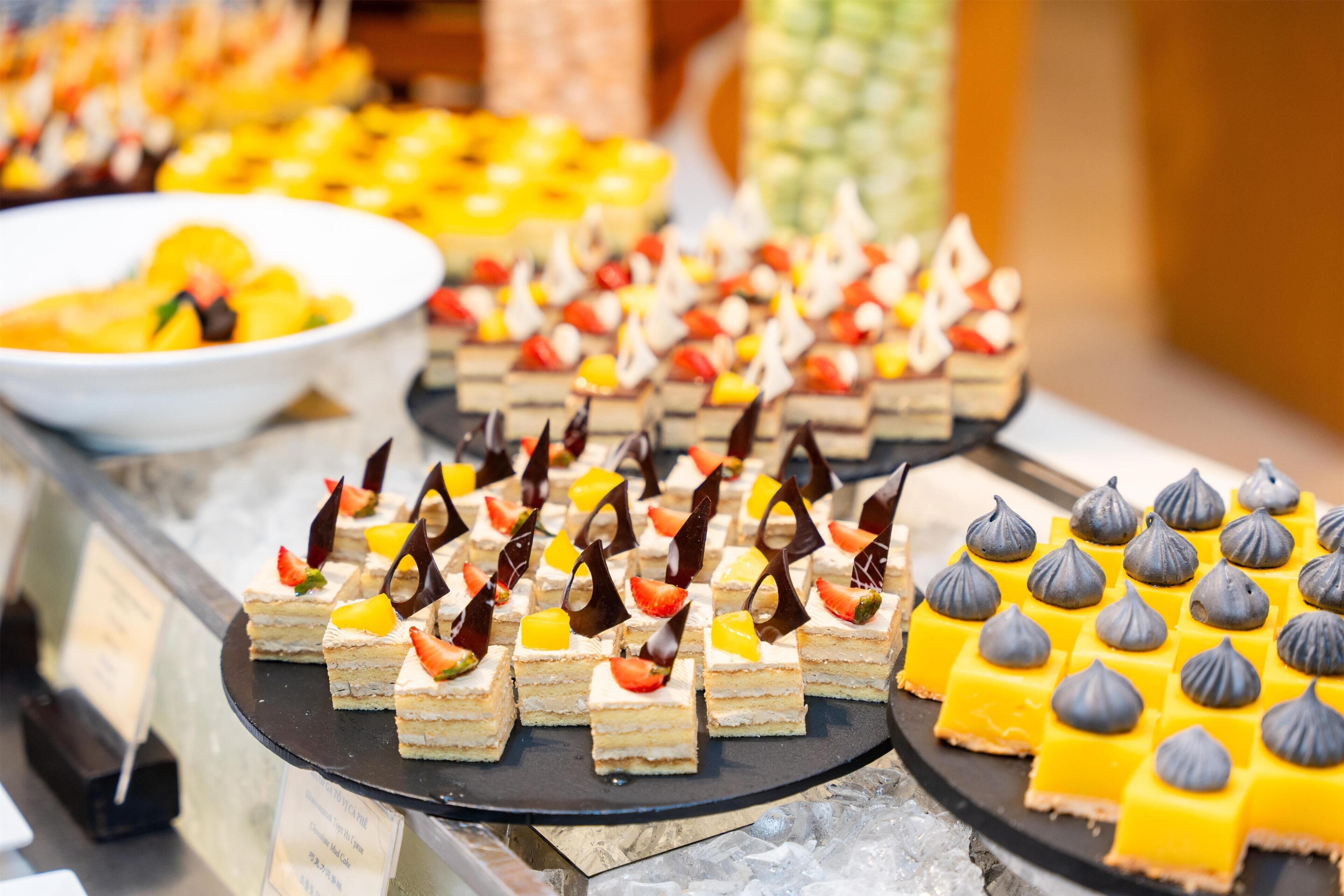 A buffet with various desserts, including layered cakes and meringue-topped squares.