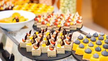 A buffet with various desserts, including layered cakes and meringue-topped squares.