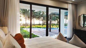 A hotel room with a large bed, a view of a swimming pool, and a tropical garden outside. - Wyndham Grand Phu Quoc (Phu Quoc)