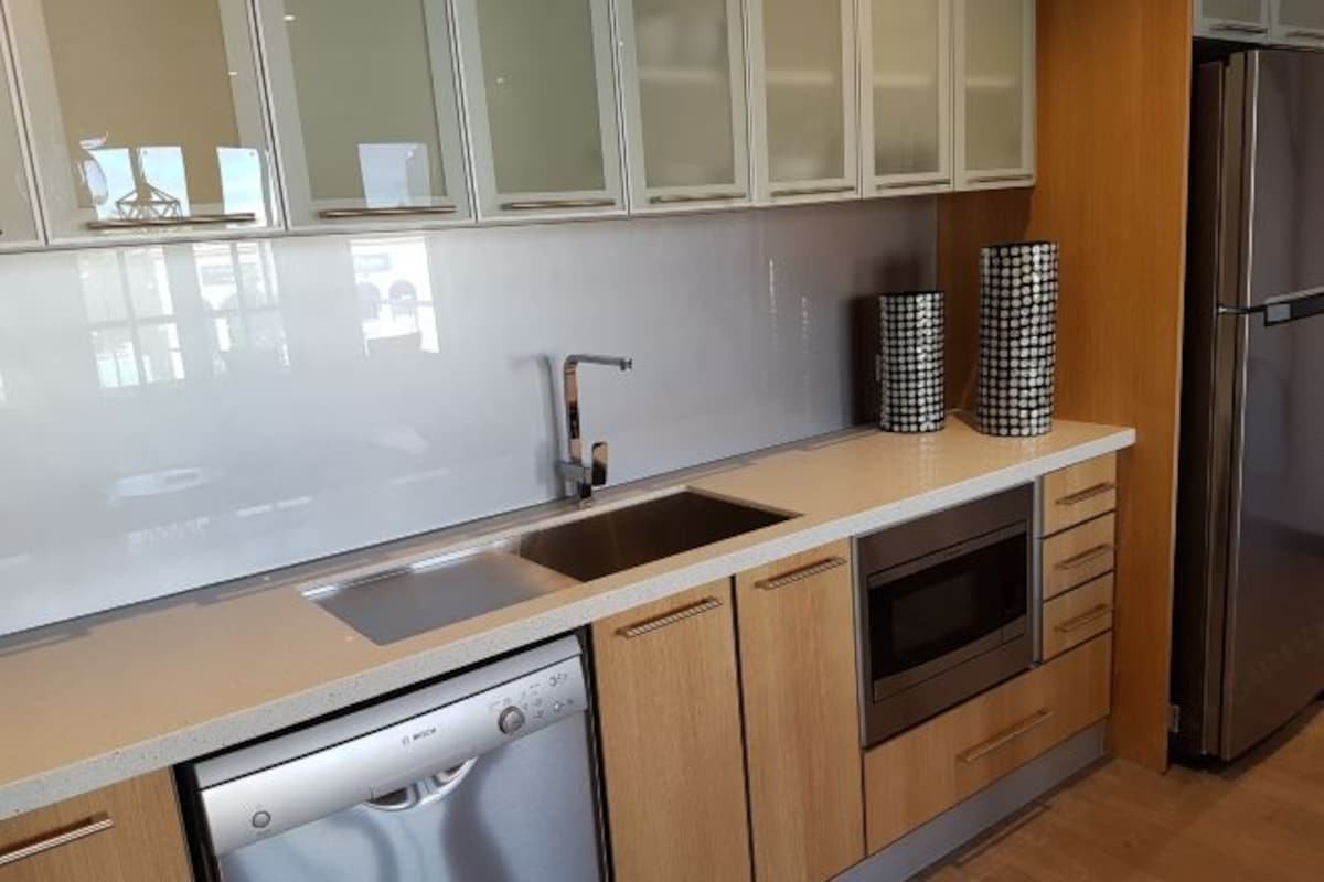 A modern kitchen with a dishwasher, oven, and stainless steel refrigerator.