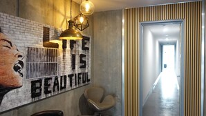 A hallway with a mural, a chair, and a door.