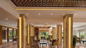 A spacious lobby with high ceilings, marble columns, and comfortable seating areas. - Hotel Grapevine (Chandauli)