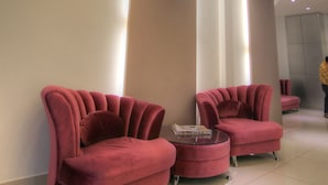 A modern lobby with two plush red sofas, a small round table, and pendant lighting.