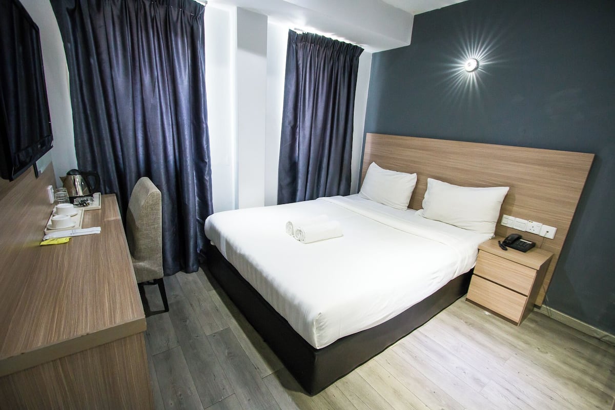 Une chambre d’hôtel comprenant un lit, une table de chevet et un bureau avec une chaise.