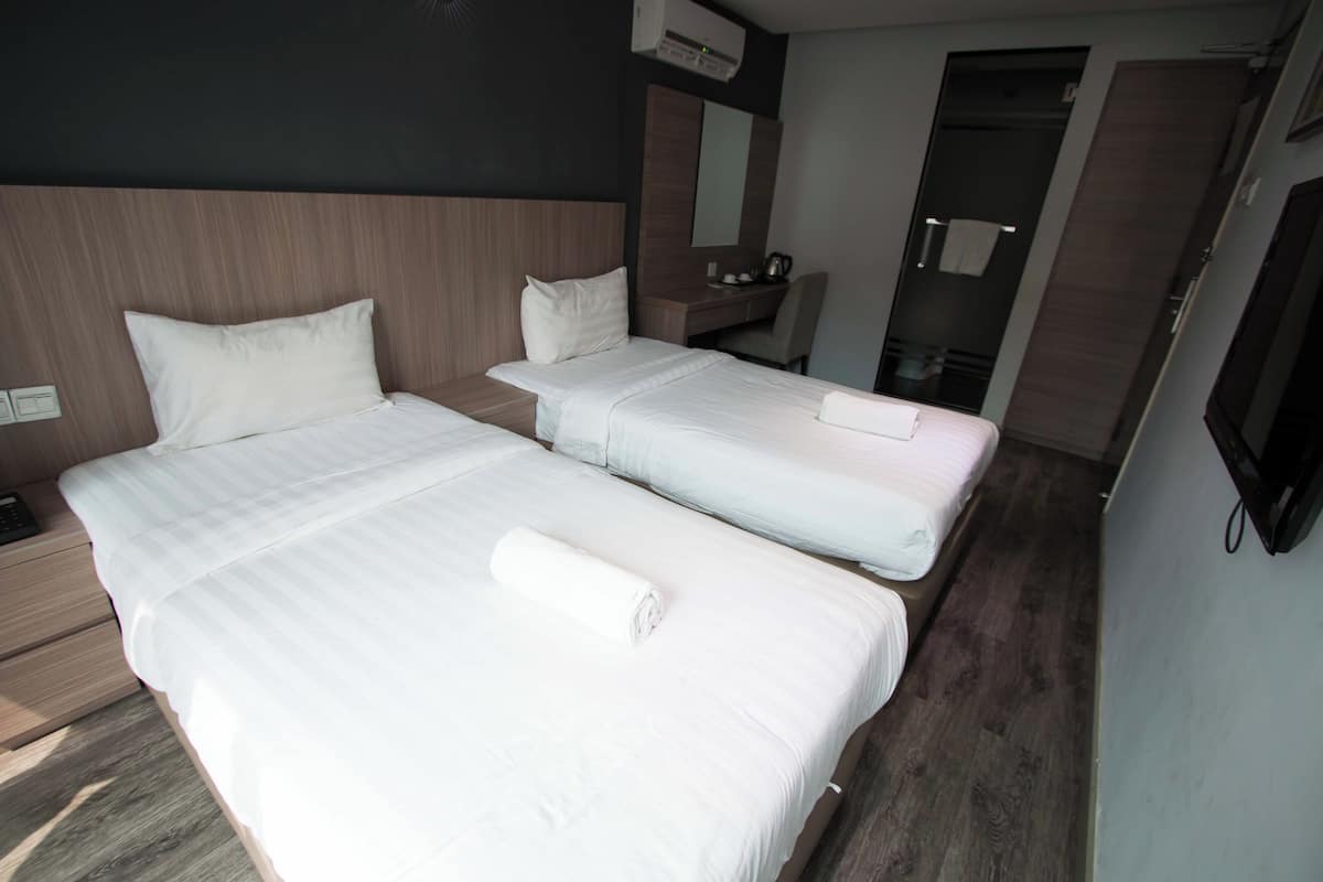 Une chambre d’hôtel avec deux lits, un bureau, un miroir et une télévision.