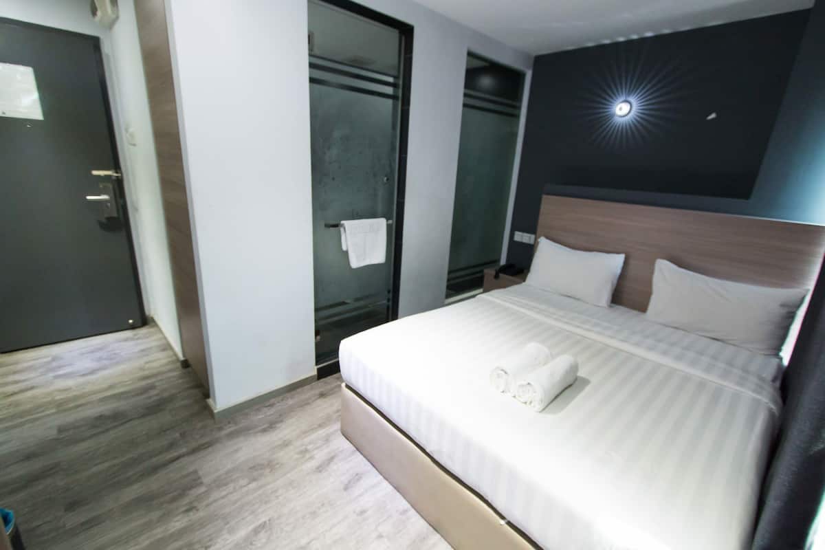 Une chambre d’hôtel avec un grand lit, une tête de lit et un luminaire au plafond.