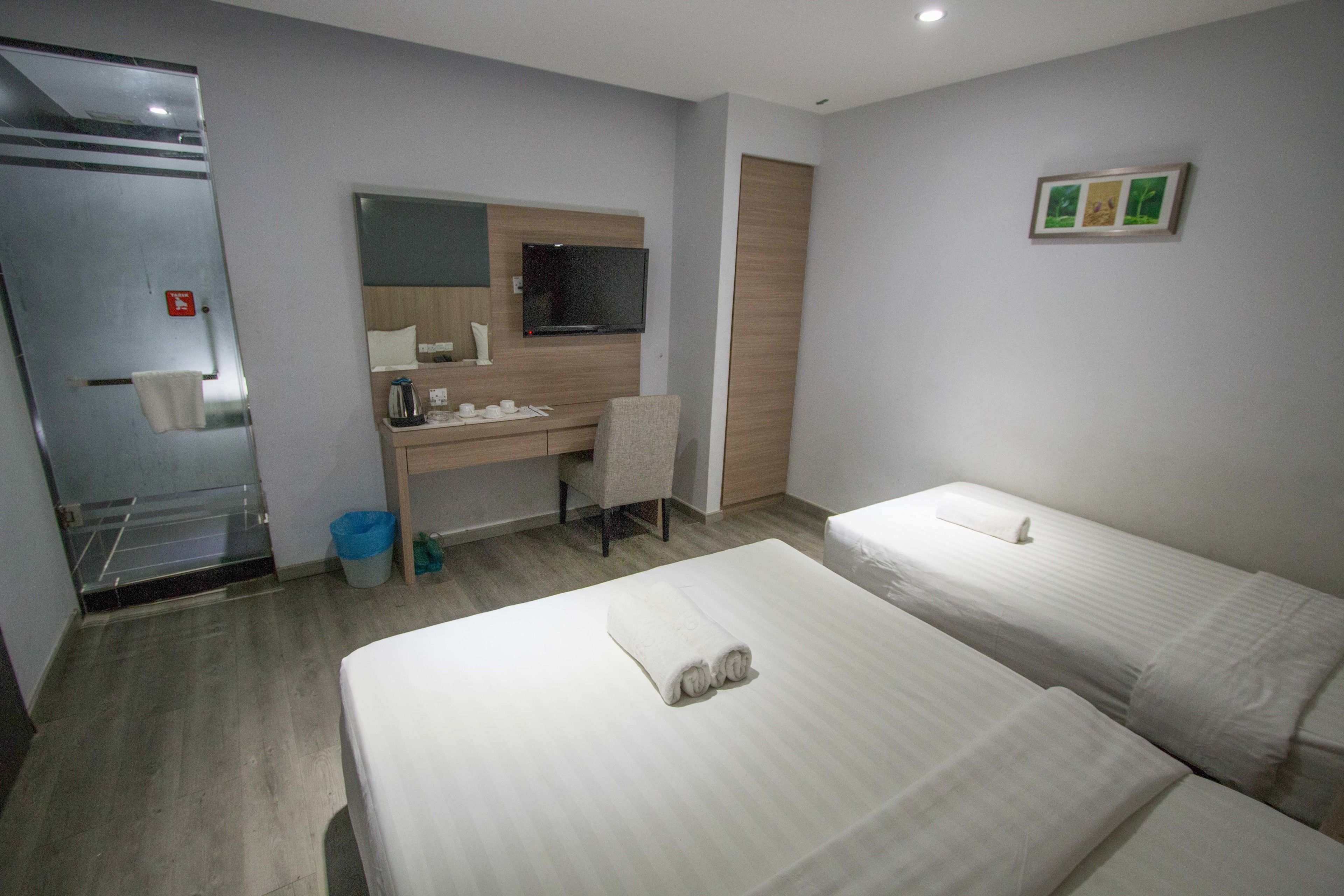 A hotel room with two beds, a desk with a chair, a TV, and a mirror.