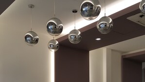A modern living room with two sofas, a decorative tree, and multiple spherical pendant lights.