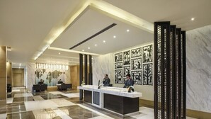 A hotel lobby with a reception desk, seating area, and decorative wall art. - Sayaji Raipur (Raipur)