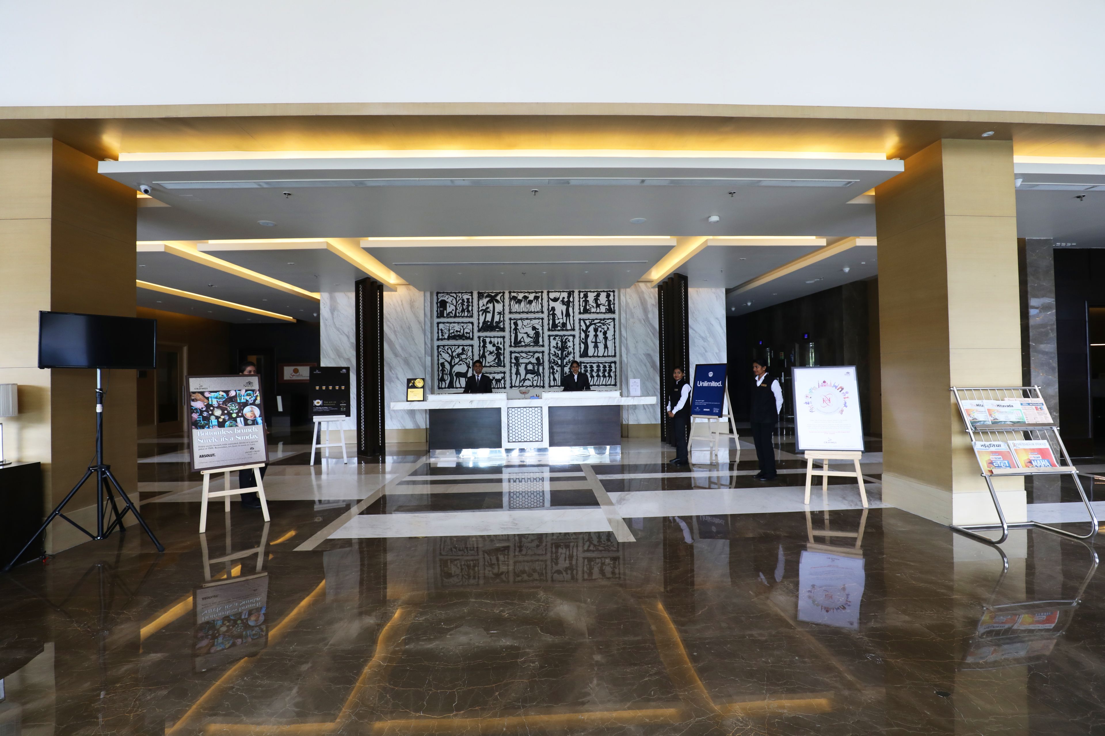 A modern lobby with a reception desk, a large wall of black-and-white artwork, and a polished marble floor.