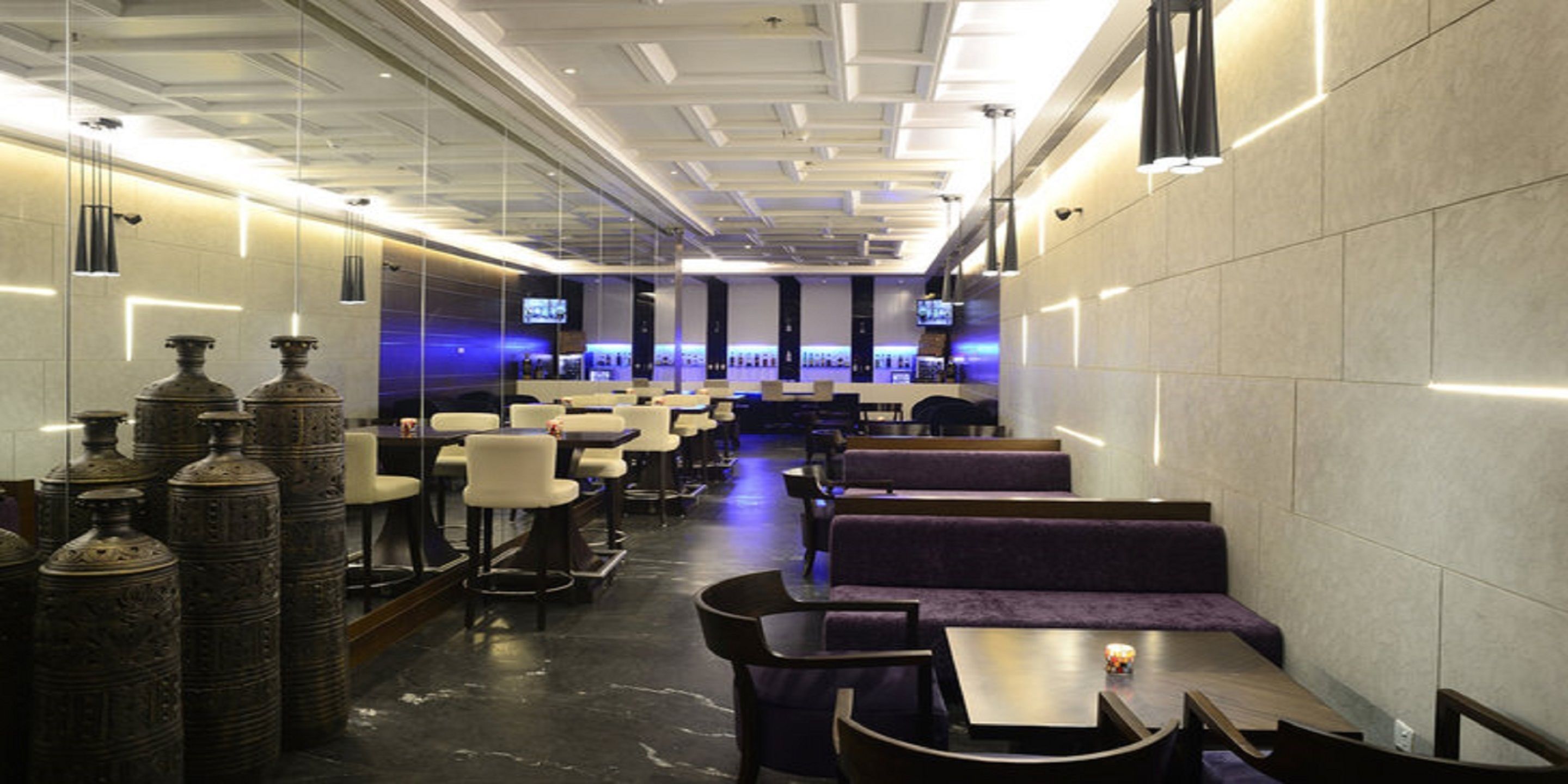 A modern restaurant with high ceilings, pendant lighting, and a long counter with seating.