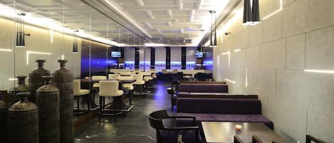 A modern restaurant with high ceilings, pendant lighting, and a long counter with seating.