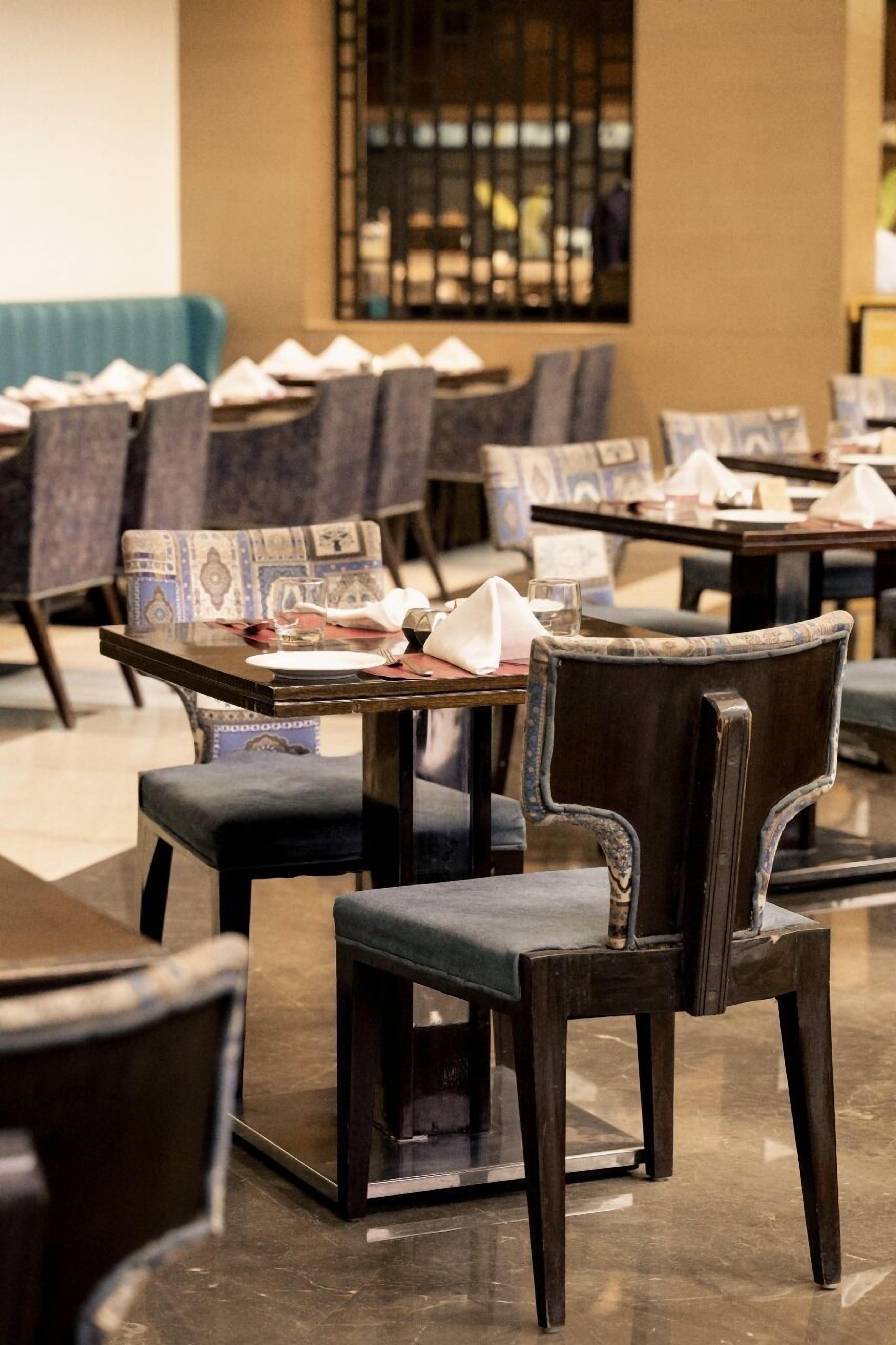 Un restaurante con mesas dispuestas para comer, con sillas de madera oscura y cojines estampados.