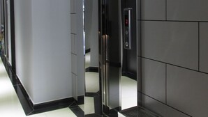 Ein moderner Aufzug mit digitaler Anzeige, einem eleganten Schwarz-Weiß-Innenraum und einer Holzvertäfelung darüber.