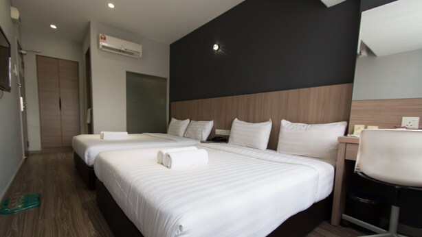 Ein Hotelzimmer mit zwei Betten, einem Schreibtisch und einem Stuhl.