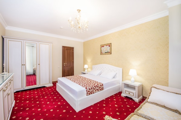 Ein Hotelzimmer mit einem großen Bett, einem Schrank, einem Nachttisch mit Lampe und einem roten Teppich.