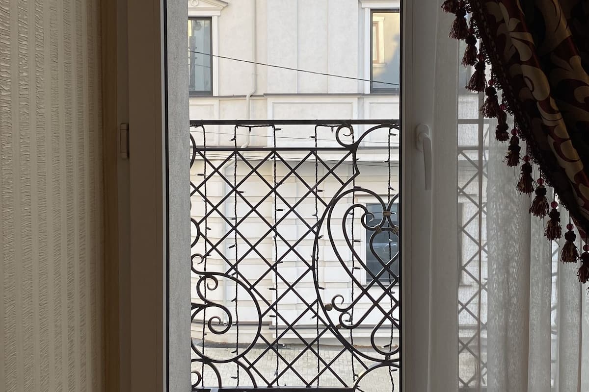 A room with a sliding glass door leading to a balcony with a decorative metal railing.