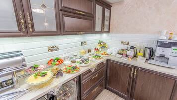A kitchen with dark wooden cabinets, a white tiled backsplash, and various food items on the counter.
