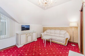 Ein Zimmer mit rotem Teppich, einem weißen Sofa und einer Kristallleuchtre.