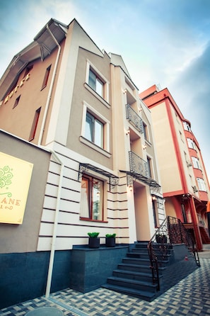 Ein mehrstöckiges Hotel mit moderner Fassade, einer sichtbaren Treppe und einem Schild, das ein Restaurant im Erdgeschoss anzeigt.