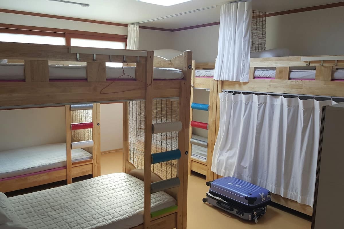 A bunk bed room with a wooden ladder, a small table, and a suitcase.