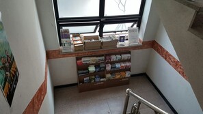 A staircase with a metal handrail, a window above, and a display of books and pamphlets on the landing.