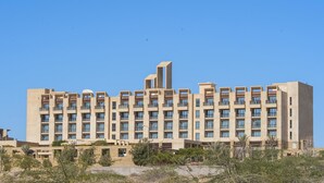 Een groot, meerlaags hotel met een modern architectonisch ontwerp, met balkons en een opvallende centrale toren.