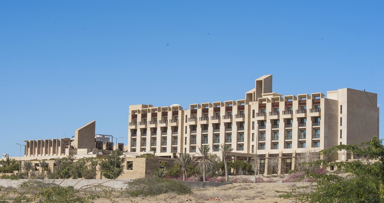 Un hotel de varios pisos con un diseño arquitectónico moderno, que incluye balcones y un techo plano.