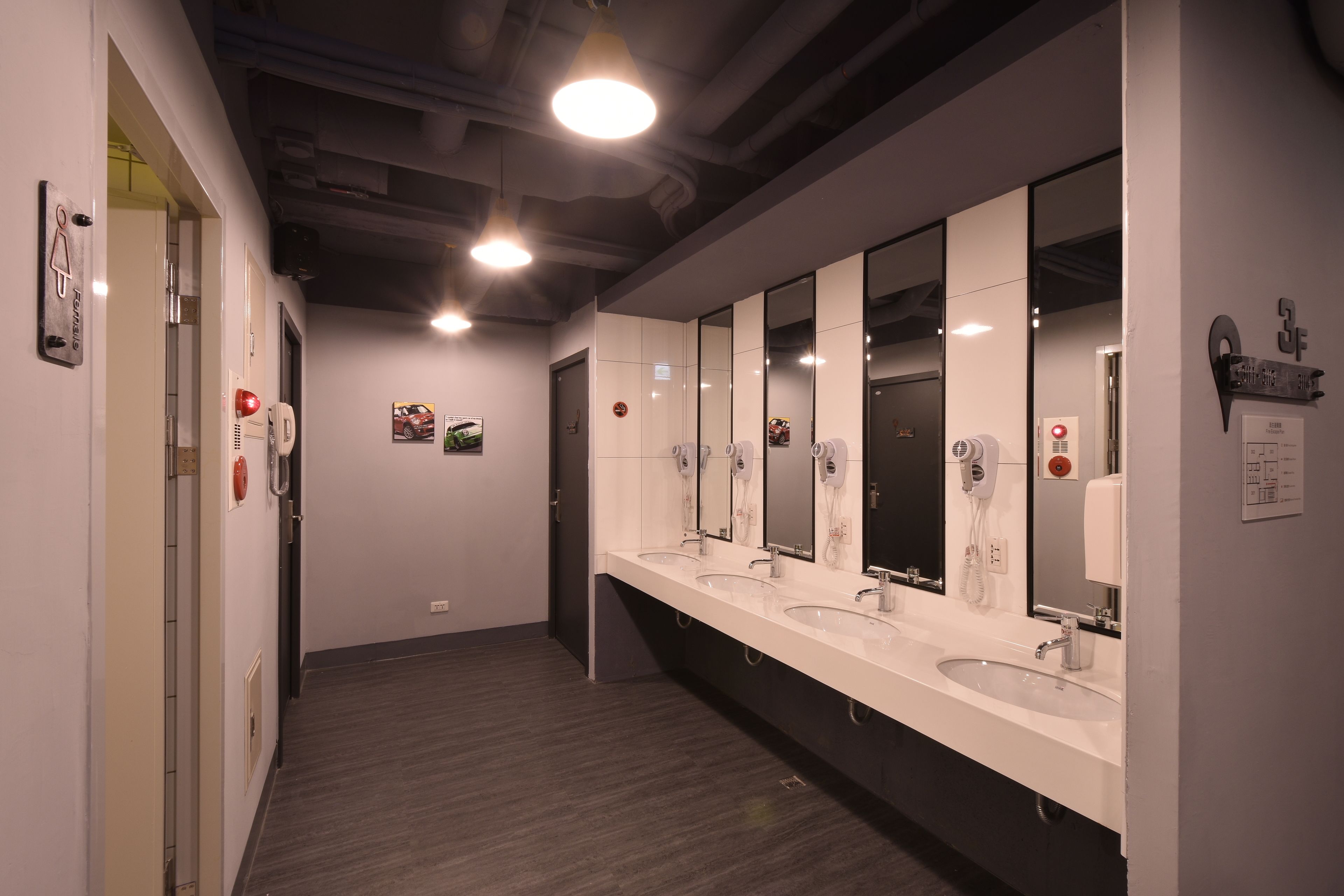 Un baño moderno con tres lavamanos, espejos grandes y suelo de madera.