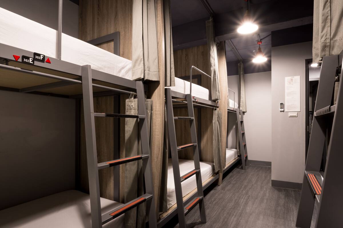 A dormitory room with bunk beds, wooden walls, and a grey floor.