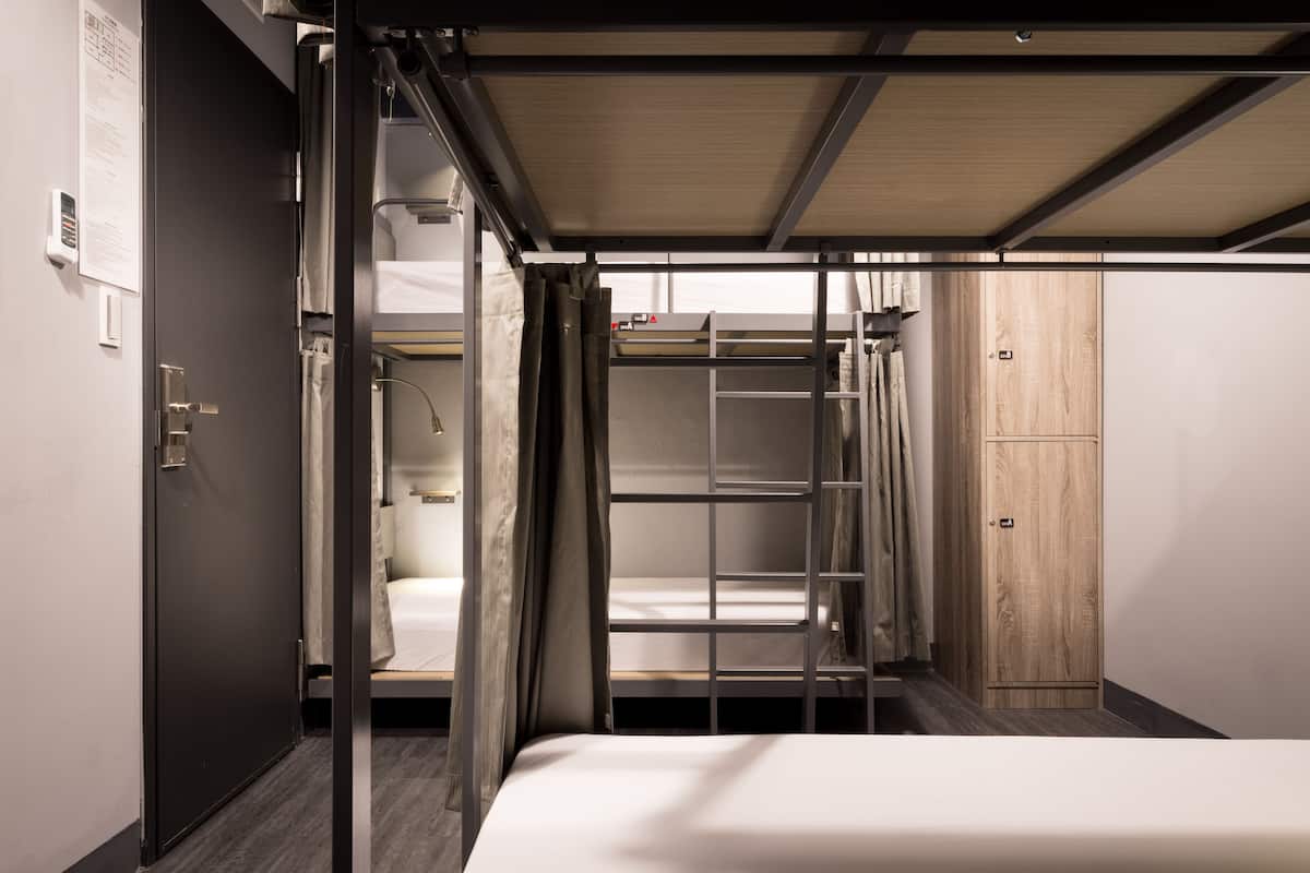 A compact hotel room with a bunk bed, a wardrobe, and a small desk area.