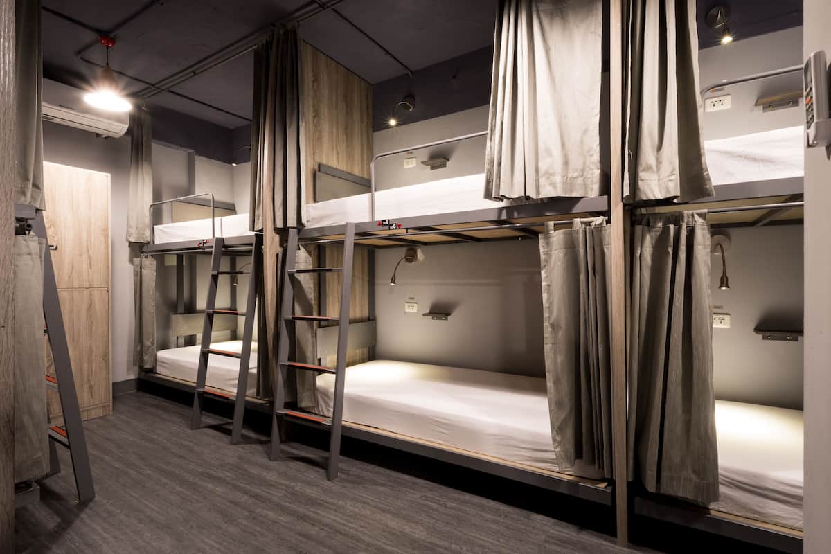 A bunk bed room with a ladder, a wooden wardrobe, and a ceiling light.